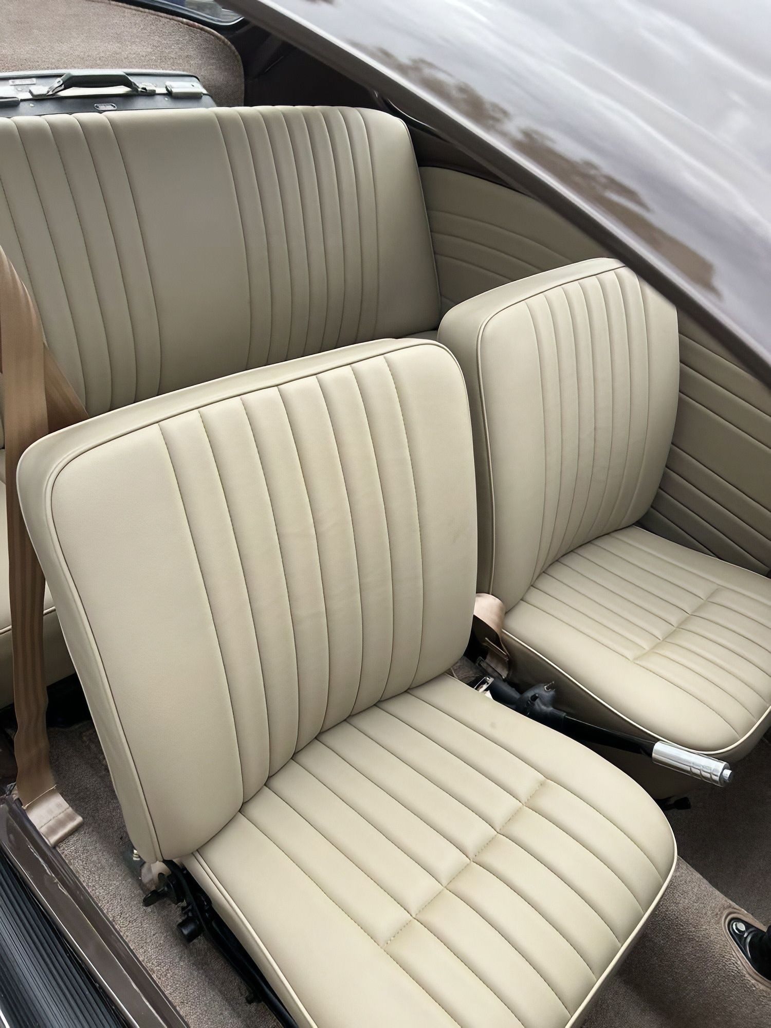 Beige leather car interior with two front seats and matching door panel upholstery