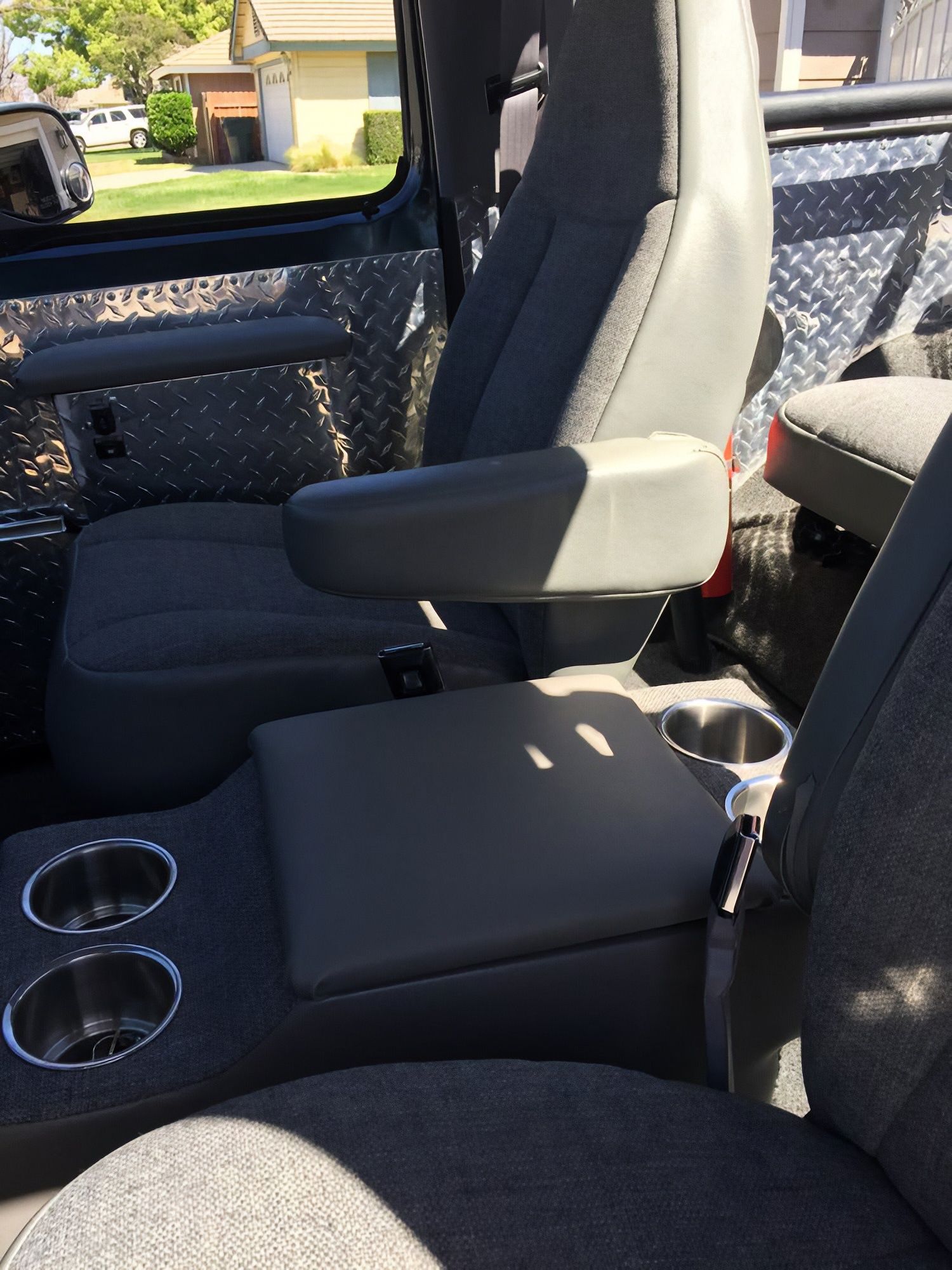 Gray pickup truck interior with front seat, center armrest, and cup holders in the console