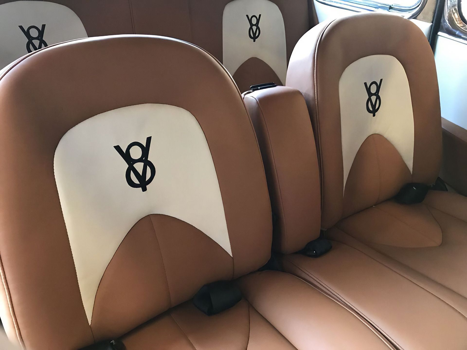 Rows of brown and cream luxury car seats with YSL logos on the headrests