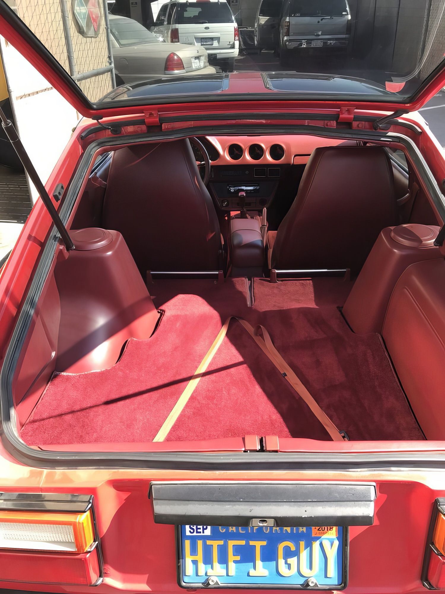 Open car trunk with red interior, custom speaker panels, and a blue HIFI GUY license plate.