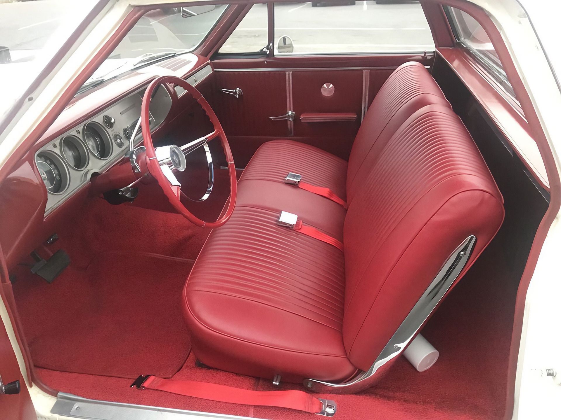 Red vintage car interior with red seats, steering wheel, and dashboard
