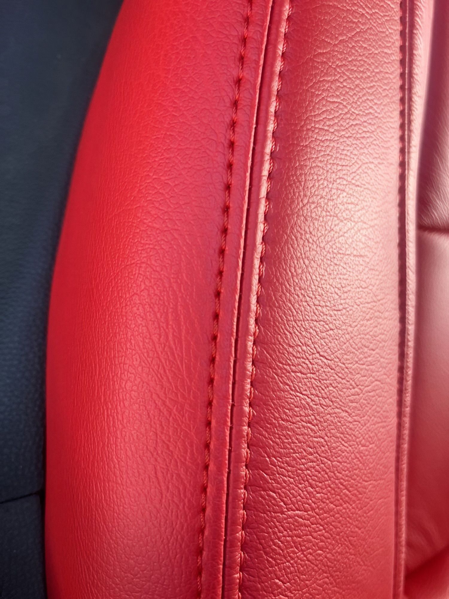Close-up of a red leather car seat with visible stitching and texture