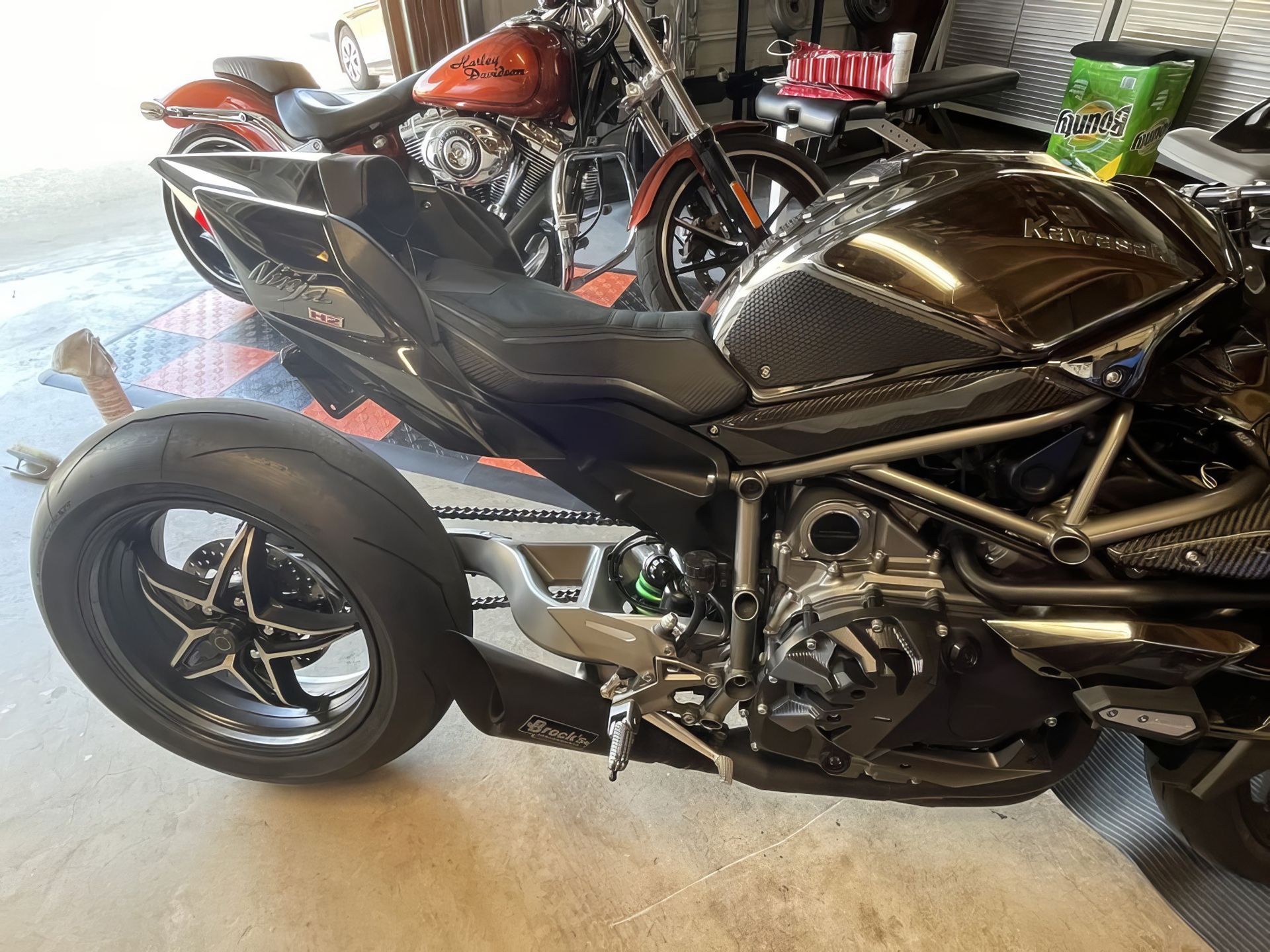 Black sport motorcycle with sidecar in a garage, with an orange motorcycle in the background