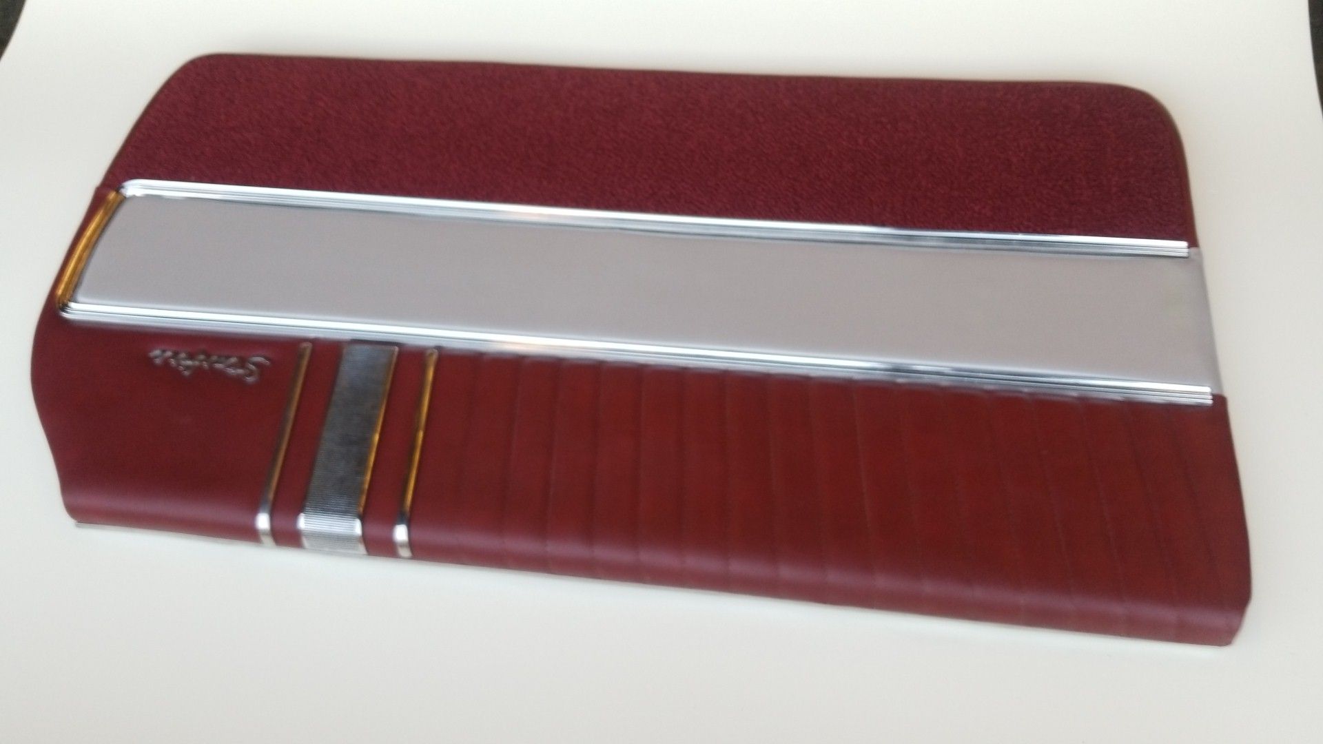 Red leather guitar case with silver trim and a horizontal silver stripe.