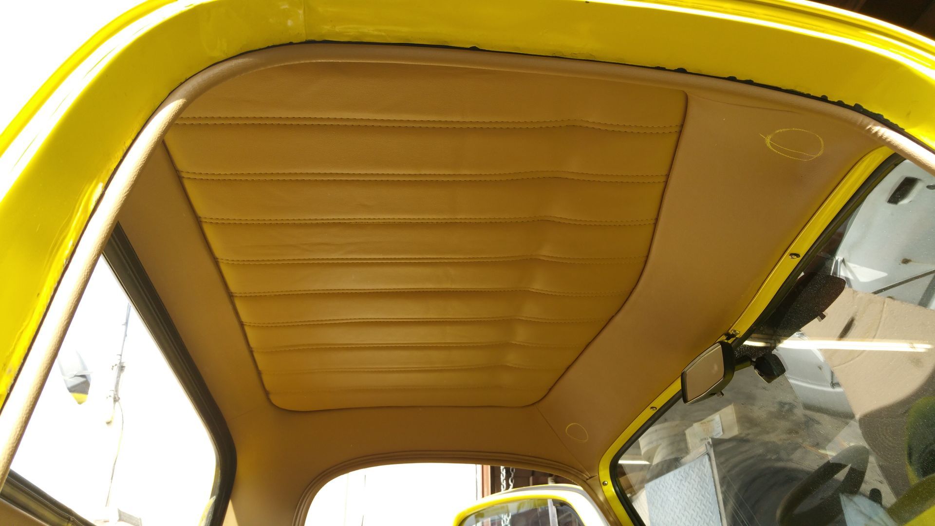 Yellow car interior roof with beige headliner and windows visible