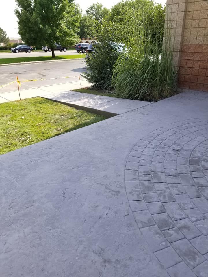 Stamped concrete patio with a decorative brick pattern, alongside grass and landscaping.