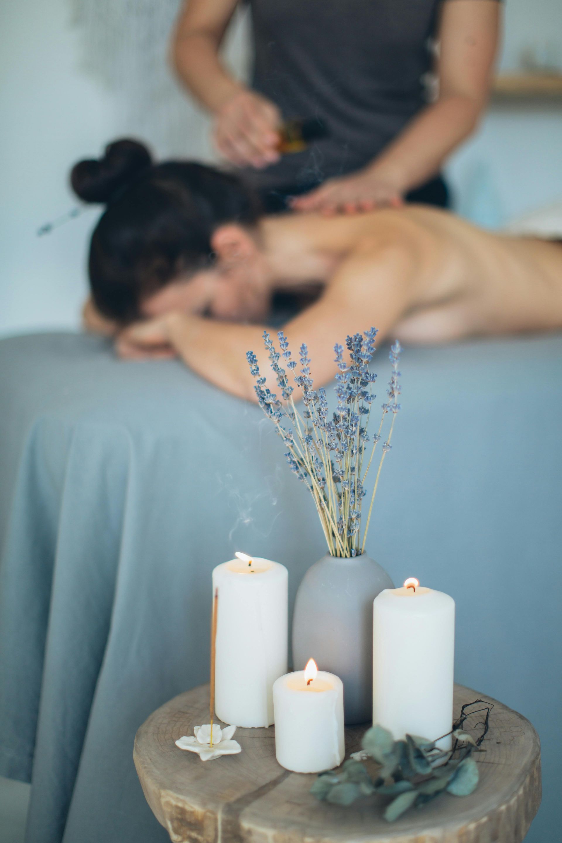 en arrière plan un massage fait un massage bien-être à une femme.
En premier plan des éléments de décoration avec des bougies et des fleurs sur un tabouret en bois.
Massage bien être, massage relaxant, massage détente, colmar, ribeauvillé, horbourg wihr, wintzenheim