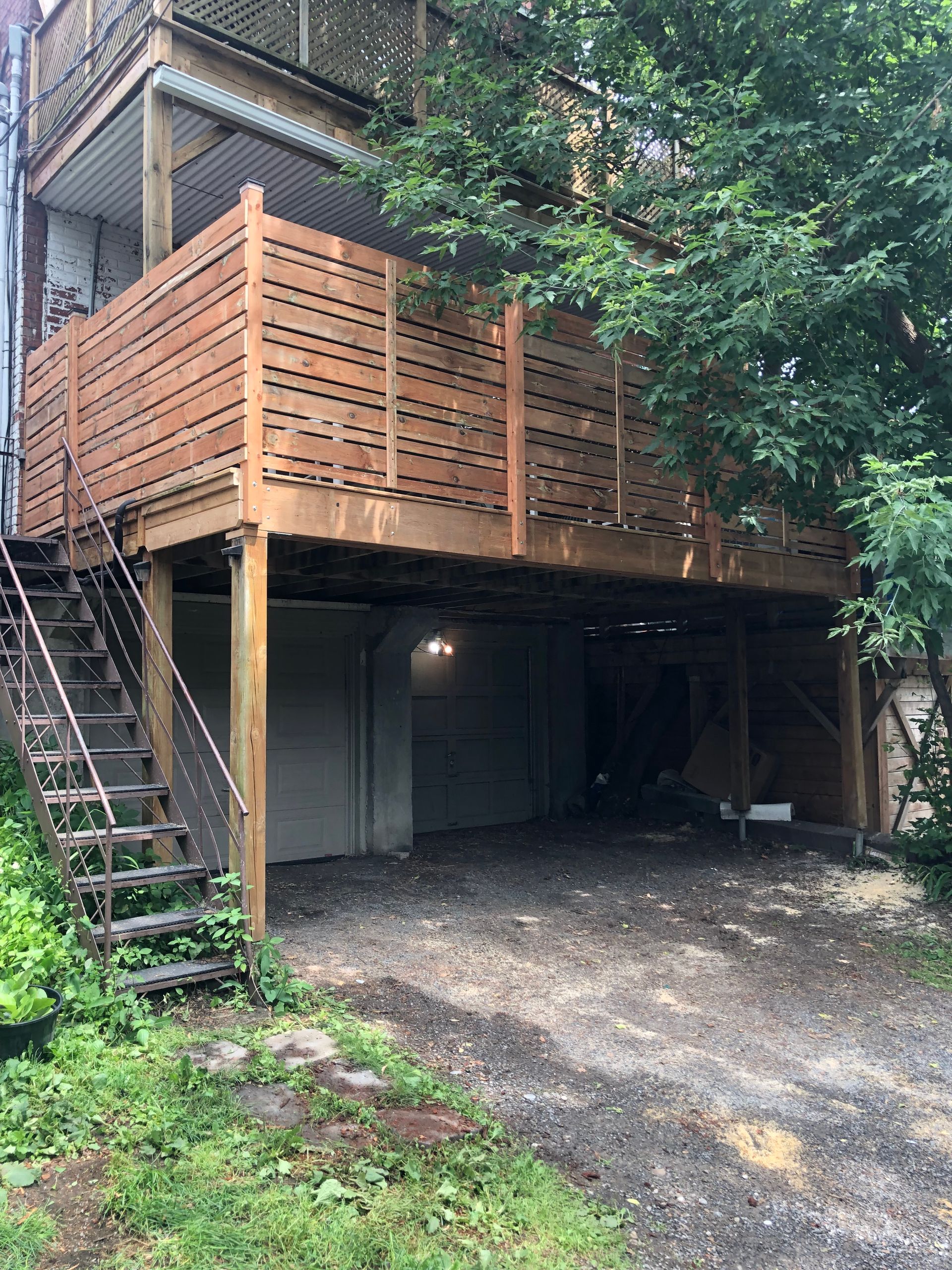 Une maison avec une terrasse en bois et des escaliers en dessous.