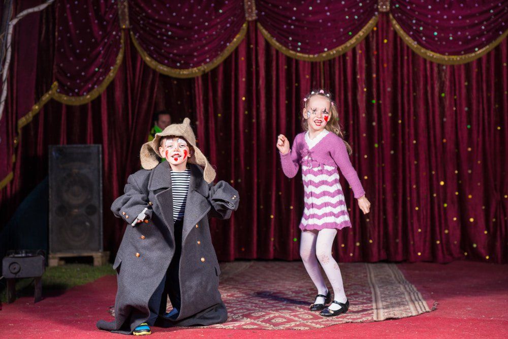 Two Children Dancing On Stage With Red Velvet Curtains — Studio Curtains & Blinds in Mount Gravatt, QLD