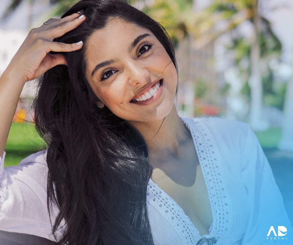 Woman smiles, hand in hair. 