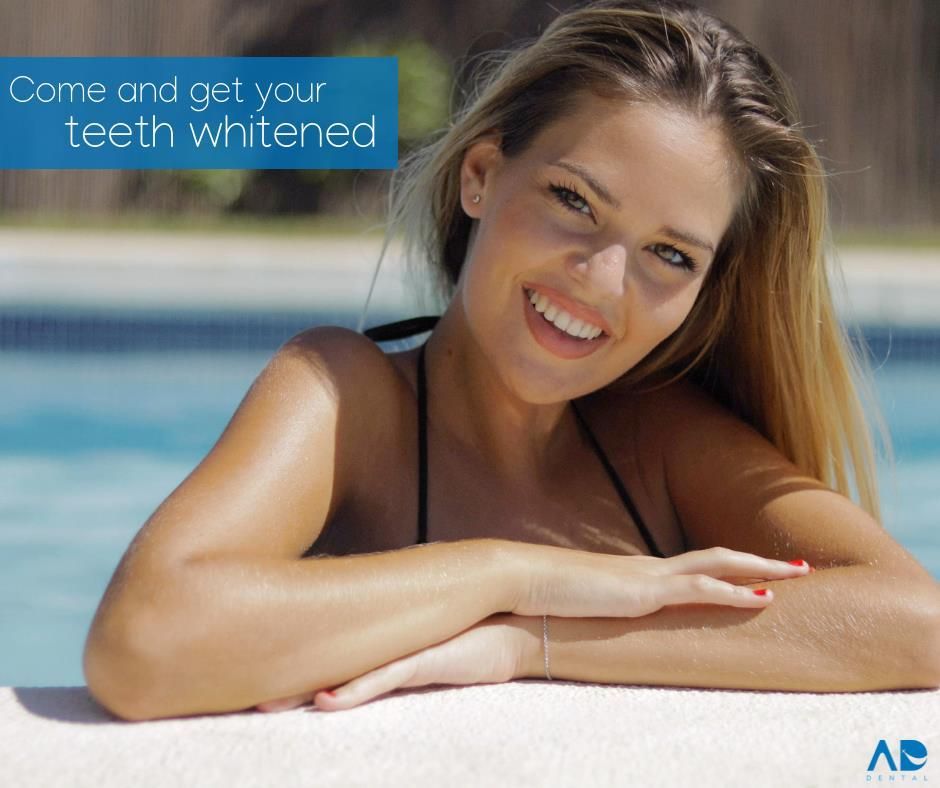 Woman smiling by a pool, advertising teeth whitening. 