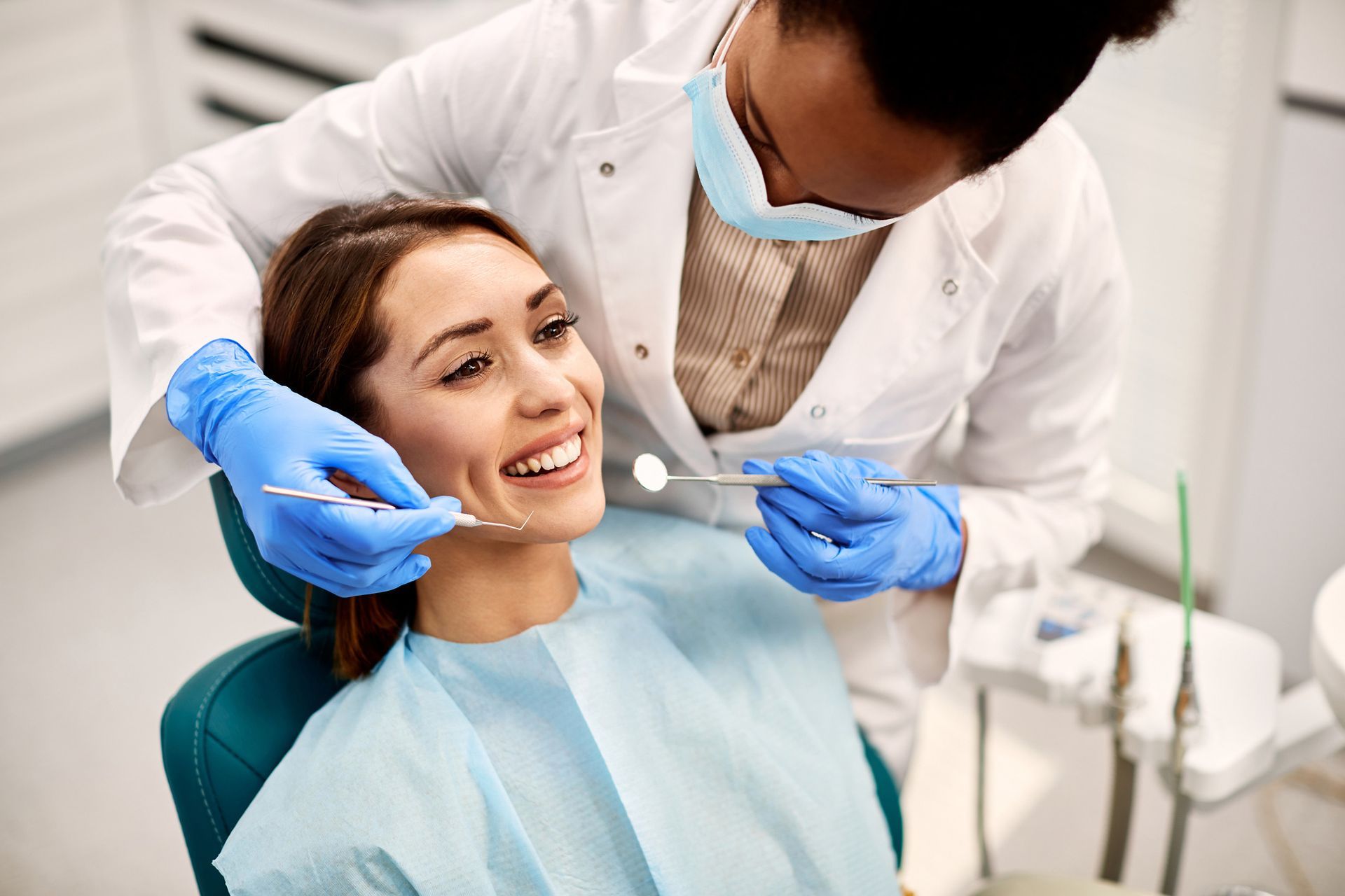 Dentist examining patient's teeth with tools in a dental office. 
