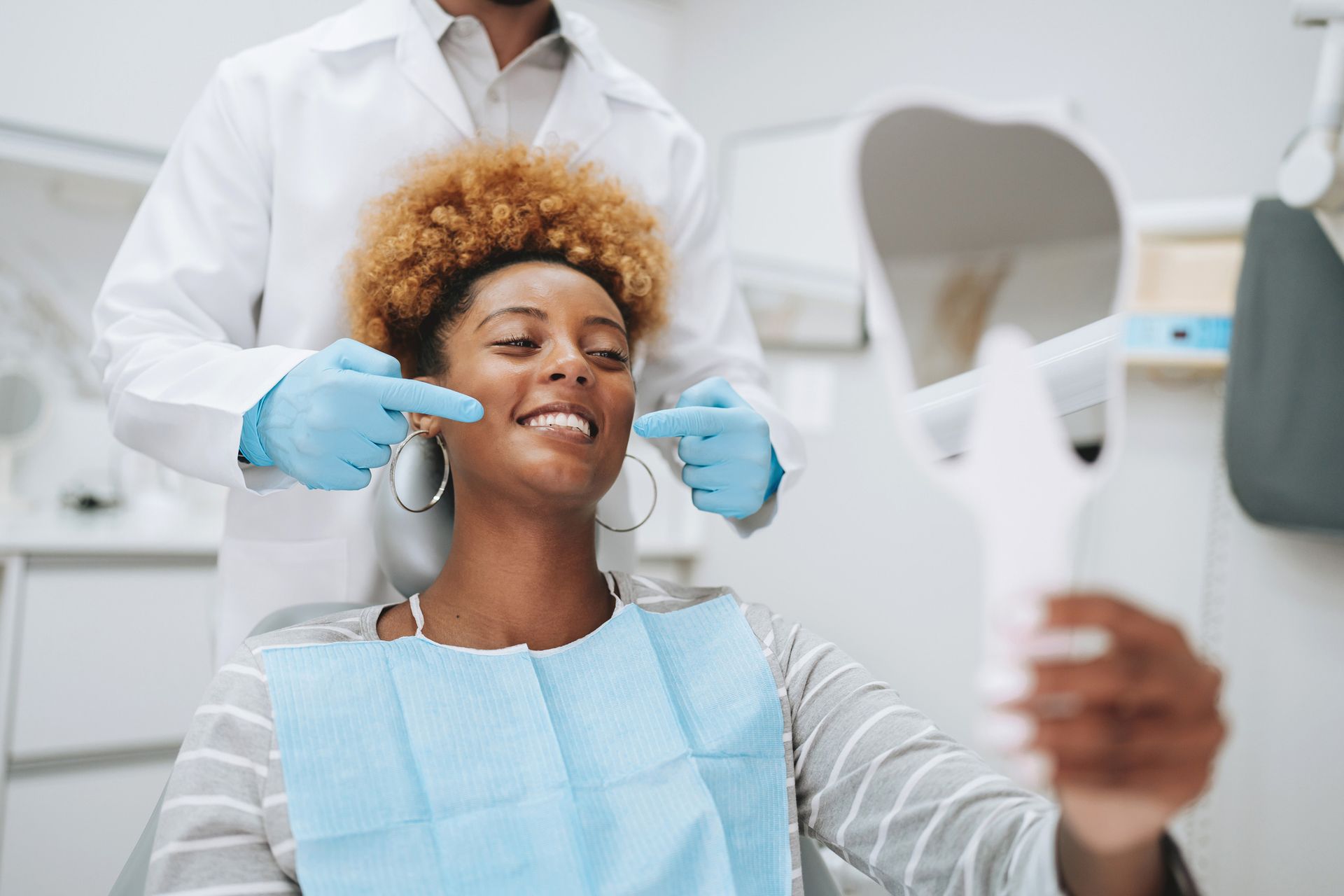 Dentist showing patient her teeth with a mirror in a dental office. 