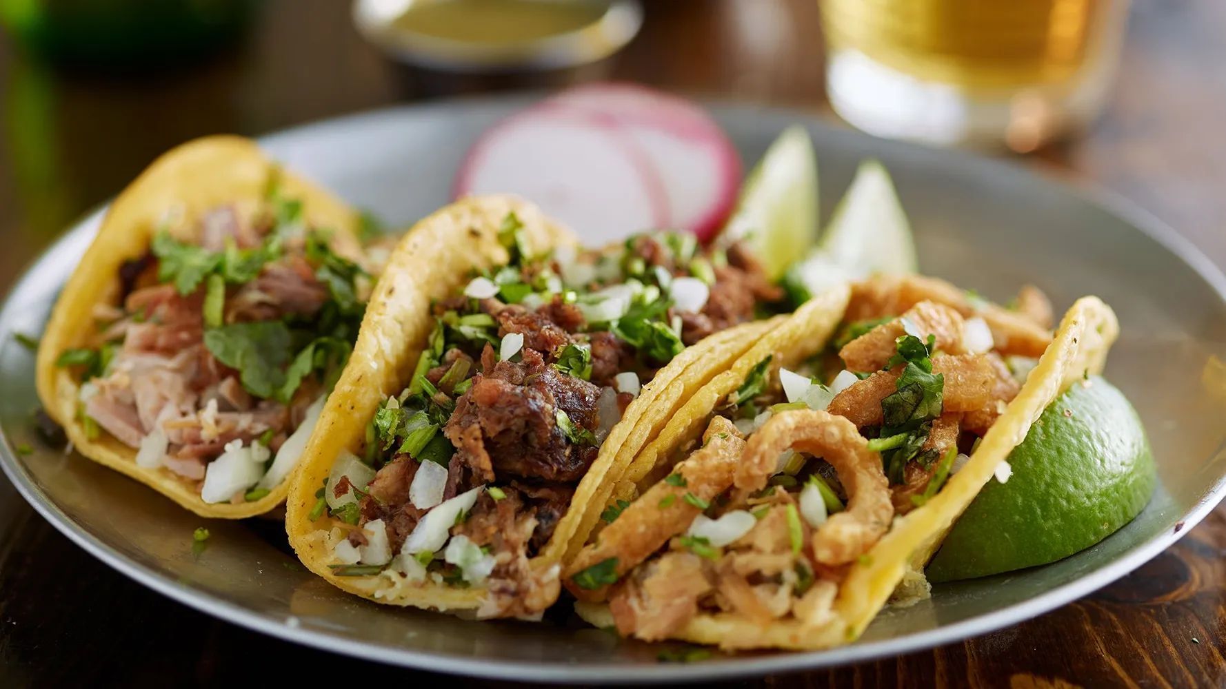 Plate of tacos with lime wedges and radish slices on a table