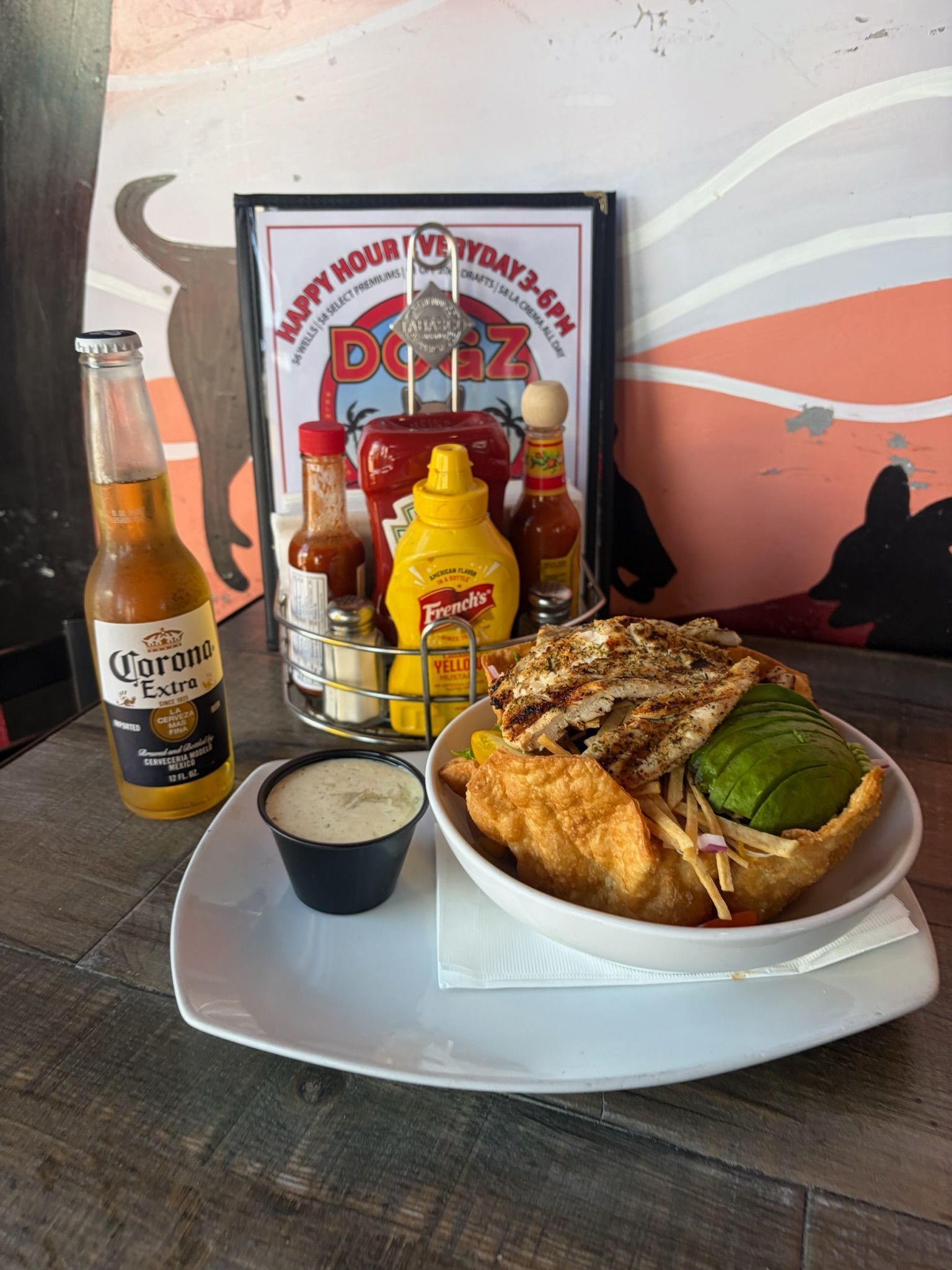 Restaurant tray with sandwich, fries, dipping sauce, and beer bottles on a table.