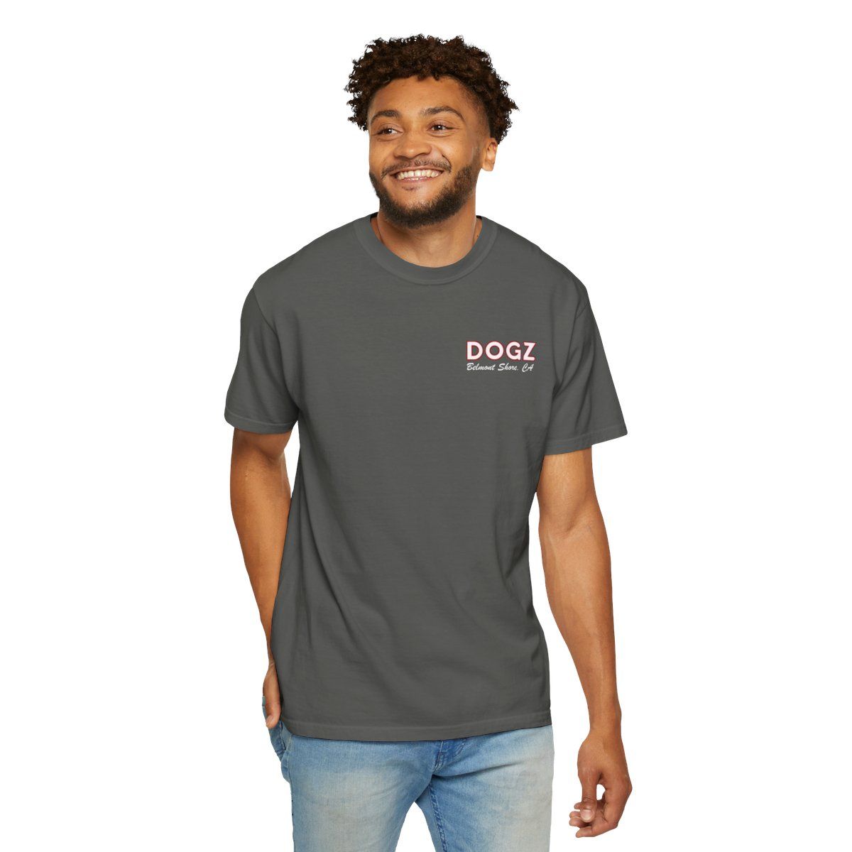 Man wearing a charcoal Dogz T-shirt and jeans, smiling against a white background