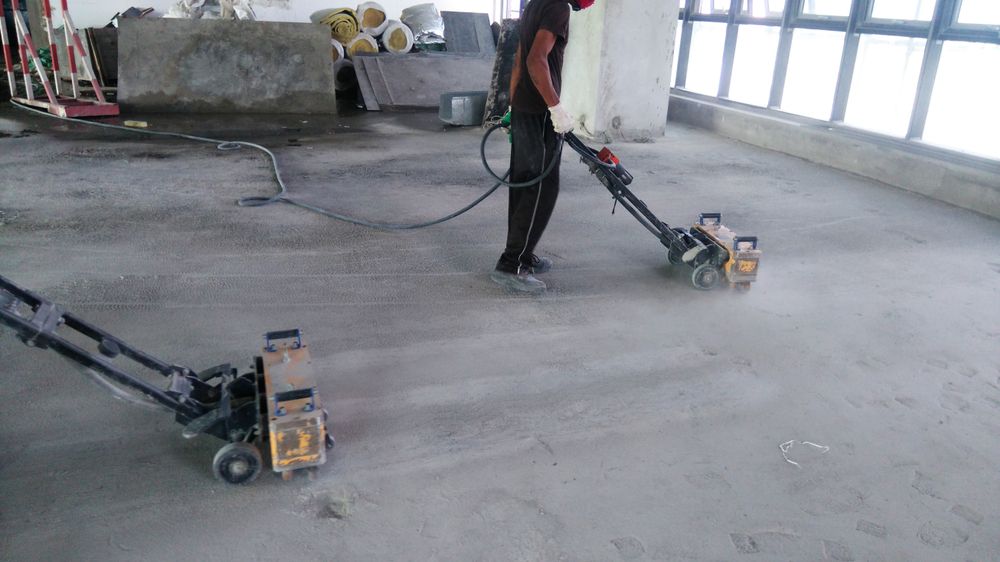 Worker Operating Two Floor-grinding Machines on a Concrete Floor in a Bright Unfinished Room — Unique Floors In New Town, TAS