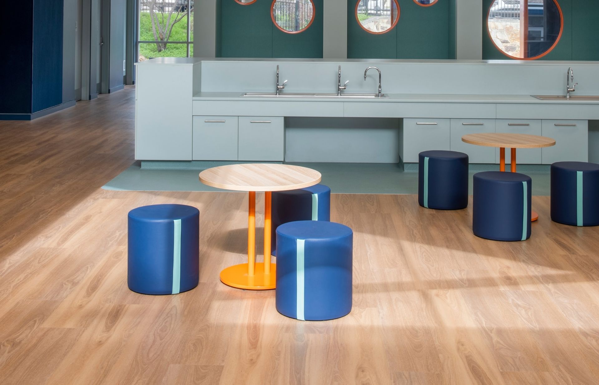 Modern lounge with blue stools, round tables, and a light wood floor in front of a mirrored counter. — Unique Floors In New Town, TAS