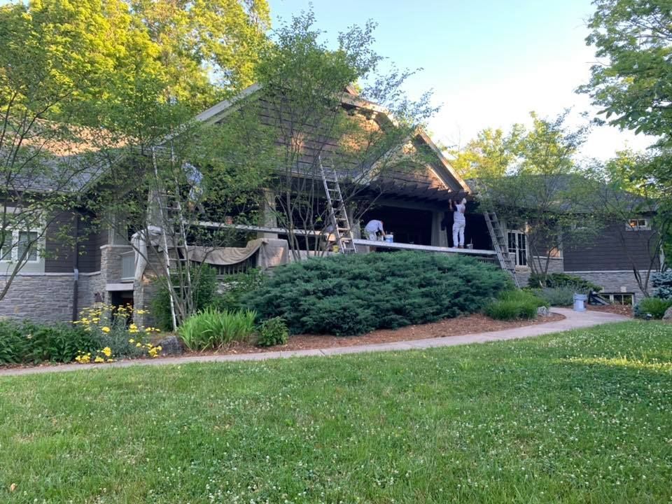 A man is painting the roof of a house.