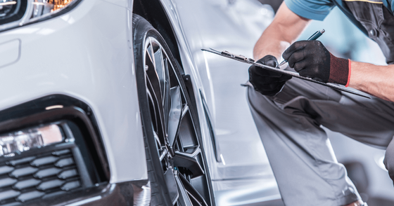 a mechanic doing a pre-purchase inspection on a white car