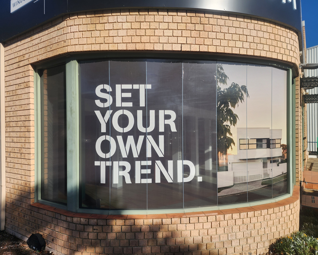 A sign on a brick building says `` set your own trend ''.
