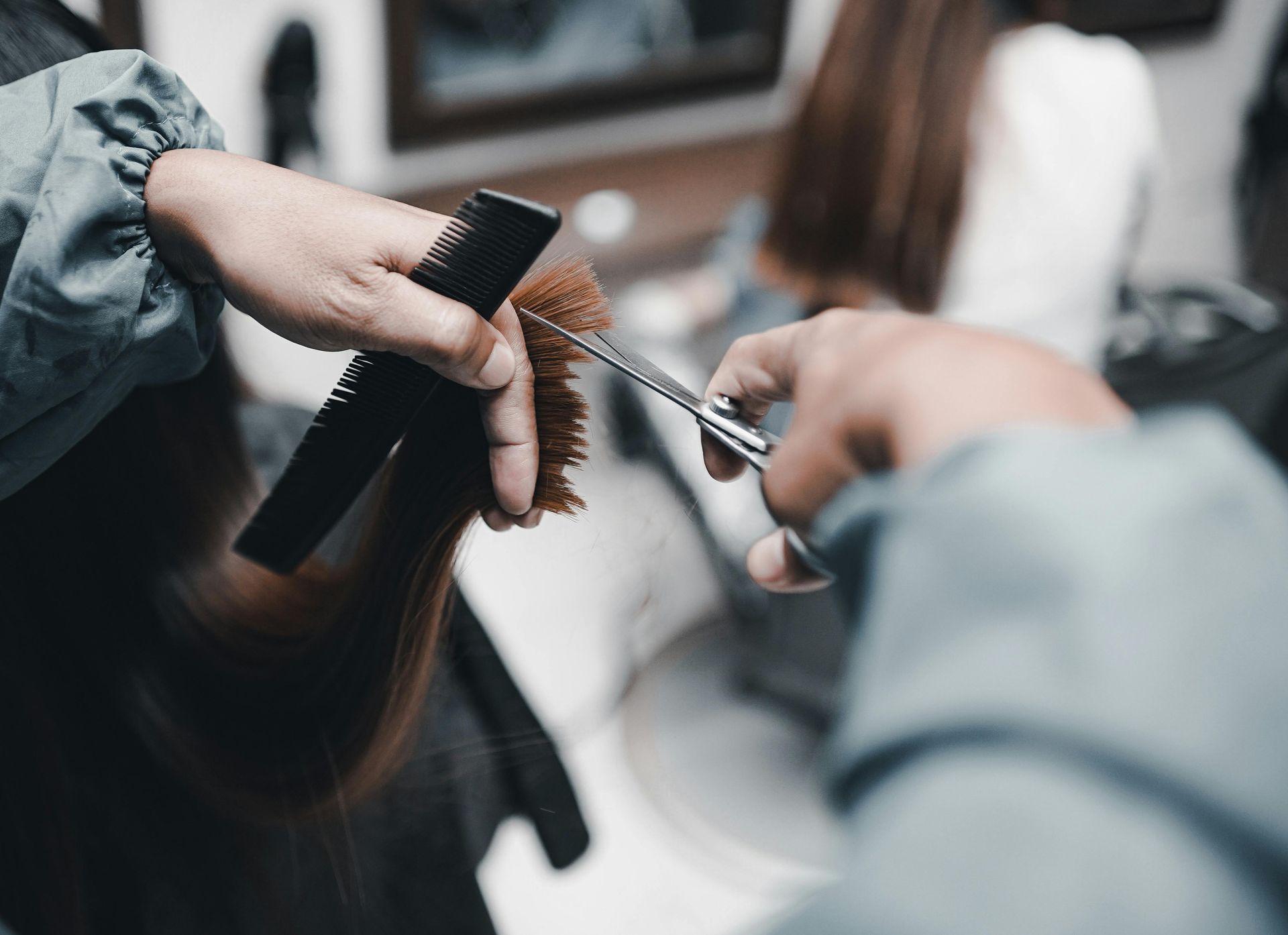 A woman is getting her hair cut by a hairdresser in a salon.