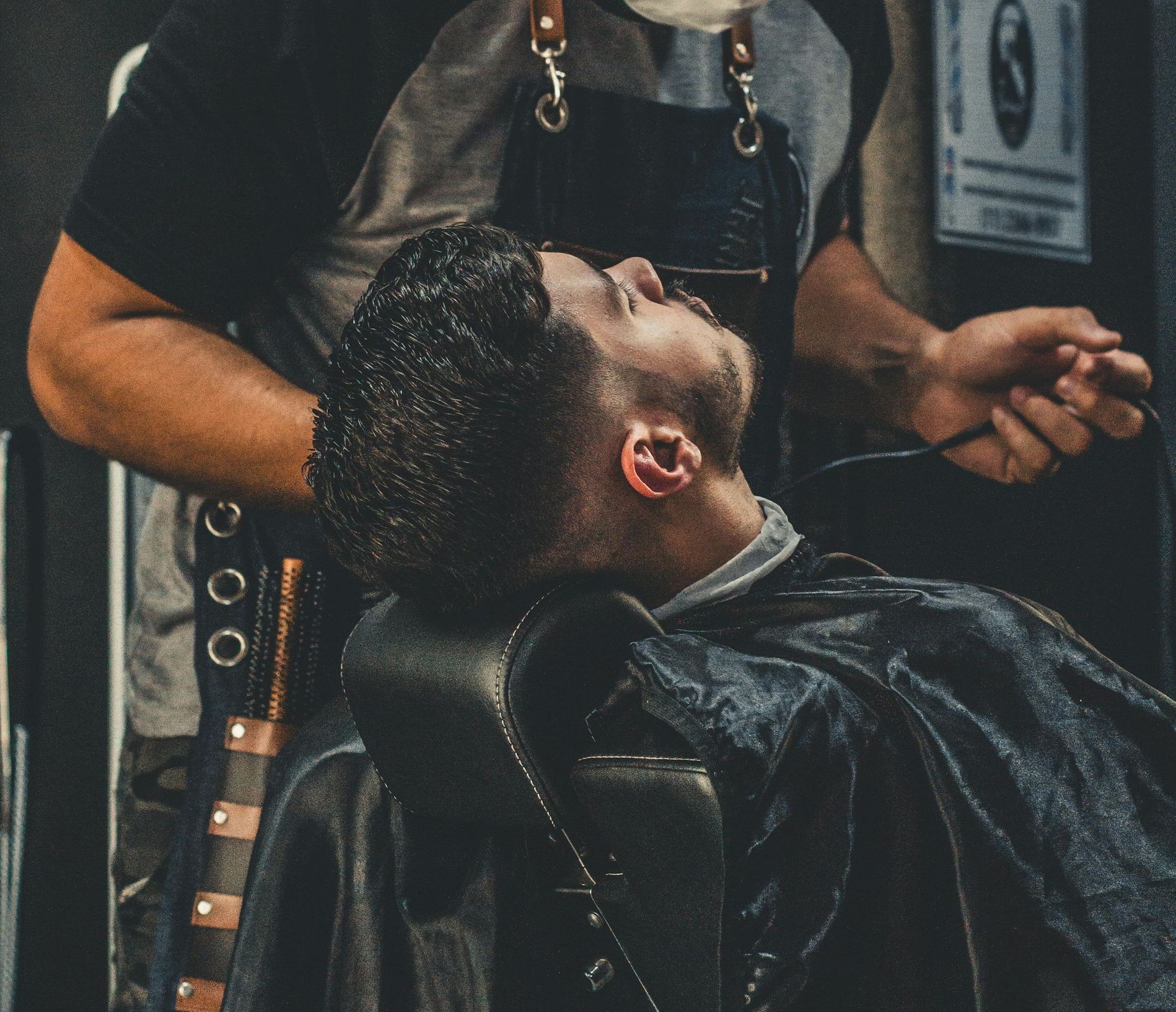 A man is getting his hair cut by a barber in a barber shop.