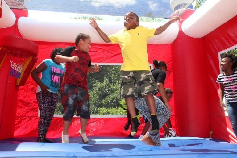 A boy in a yellow shirt is jumping in a bouncy house