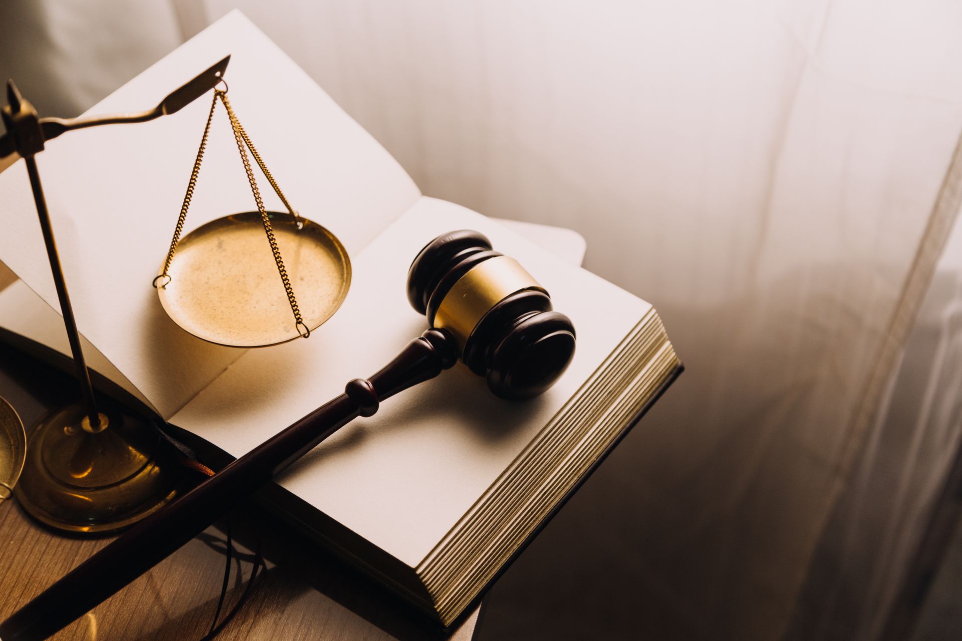 Gavel and balance scale on open book, symbolizing law and justice.