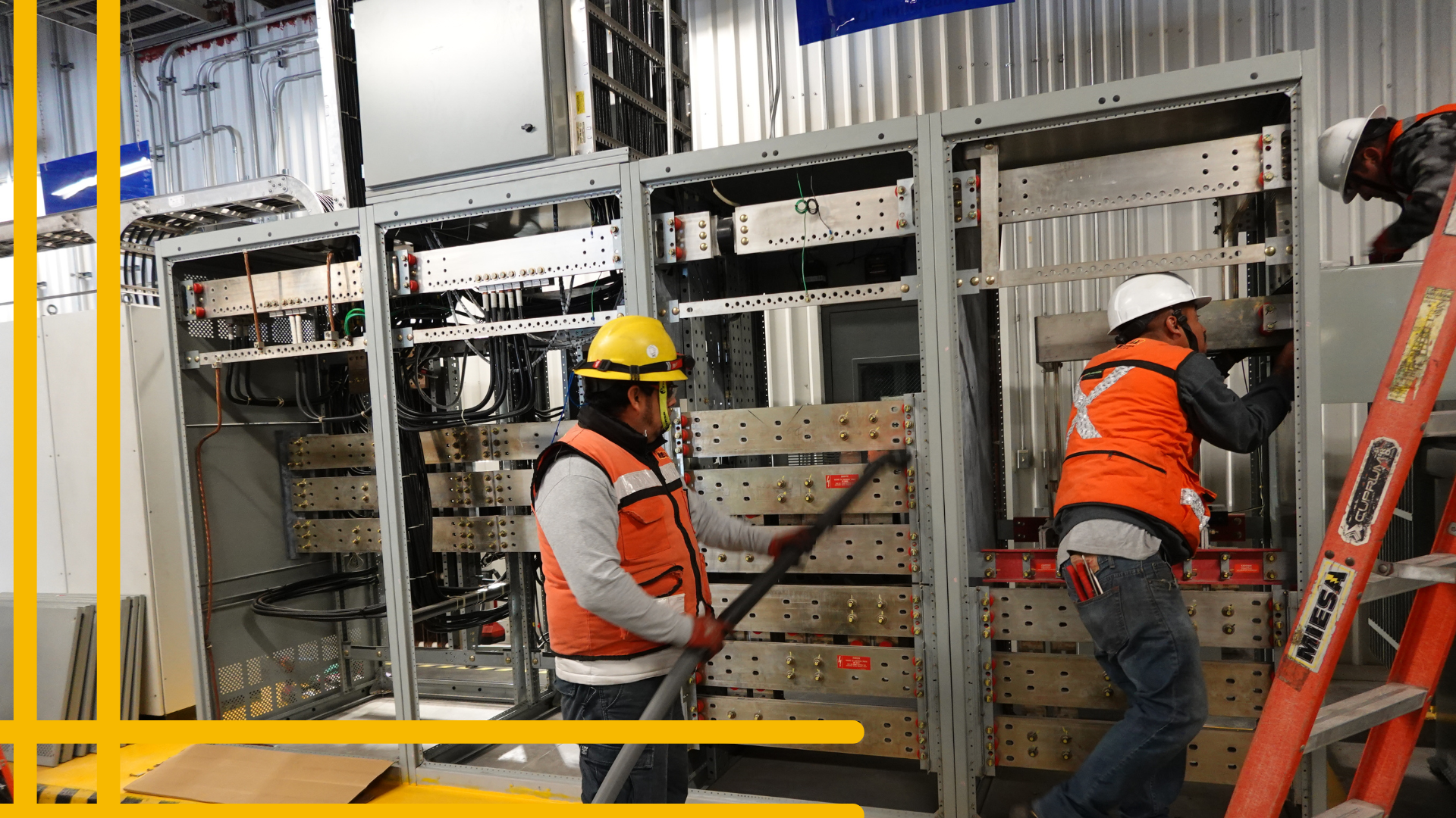 Dos hombres están trabajando en una caja eléctrica en una fábrica.