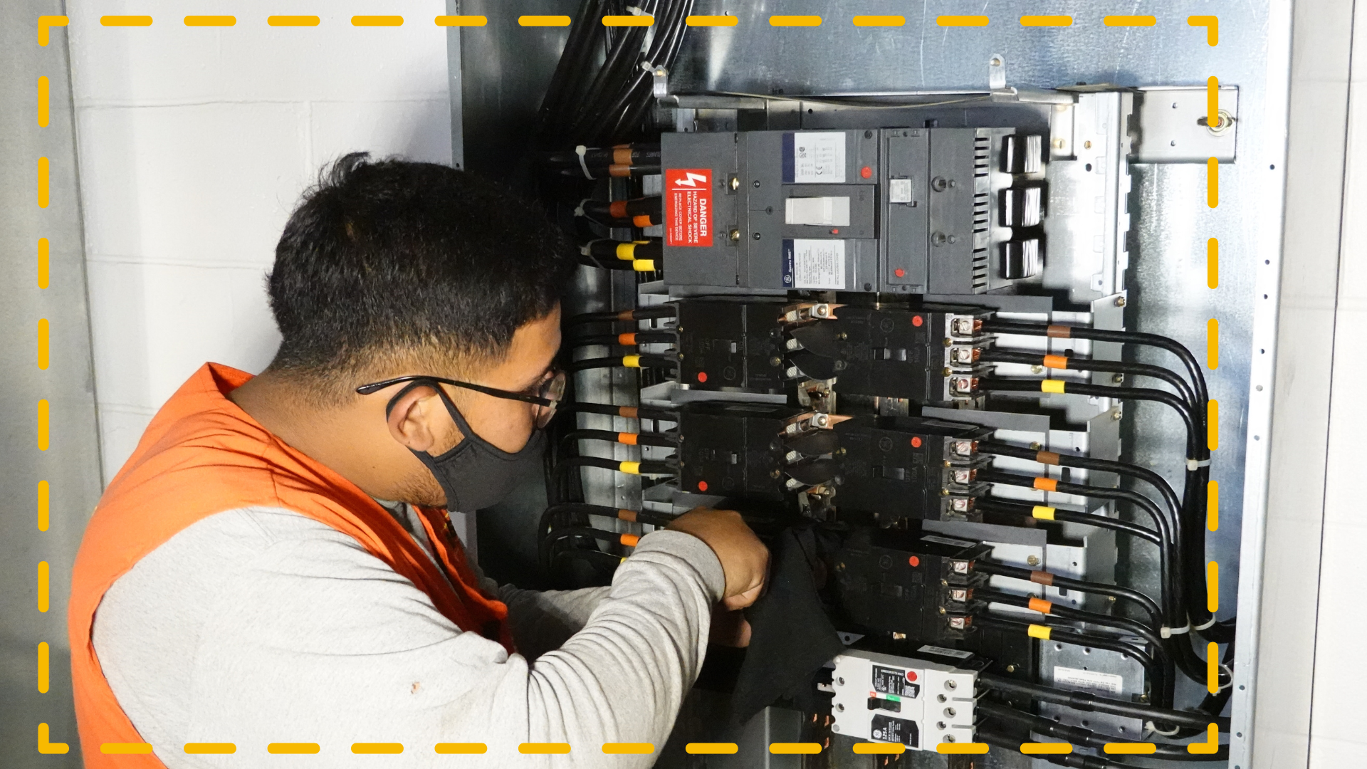 Un hombre que lleva una máscara está trabajando en una caja eléctrica.