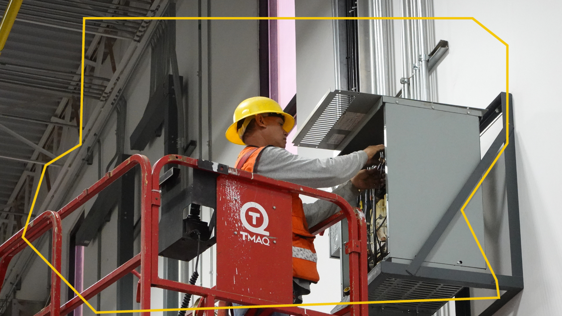 Un hombre con un casco amarillo está trabajando en una máquina en un elevador.