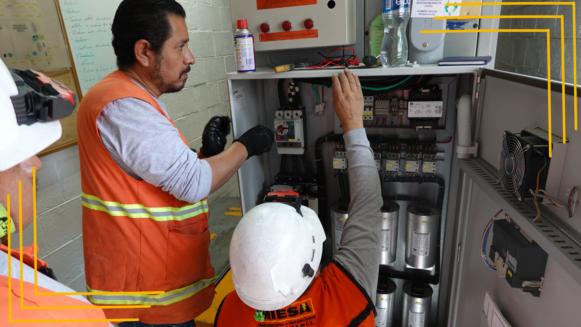 Dos hombres están trabajando en una caja eléctrica en una habitación.