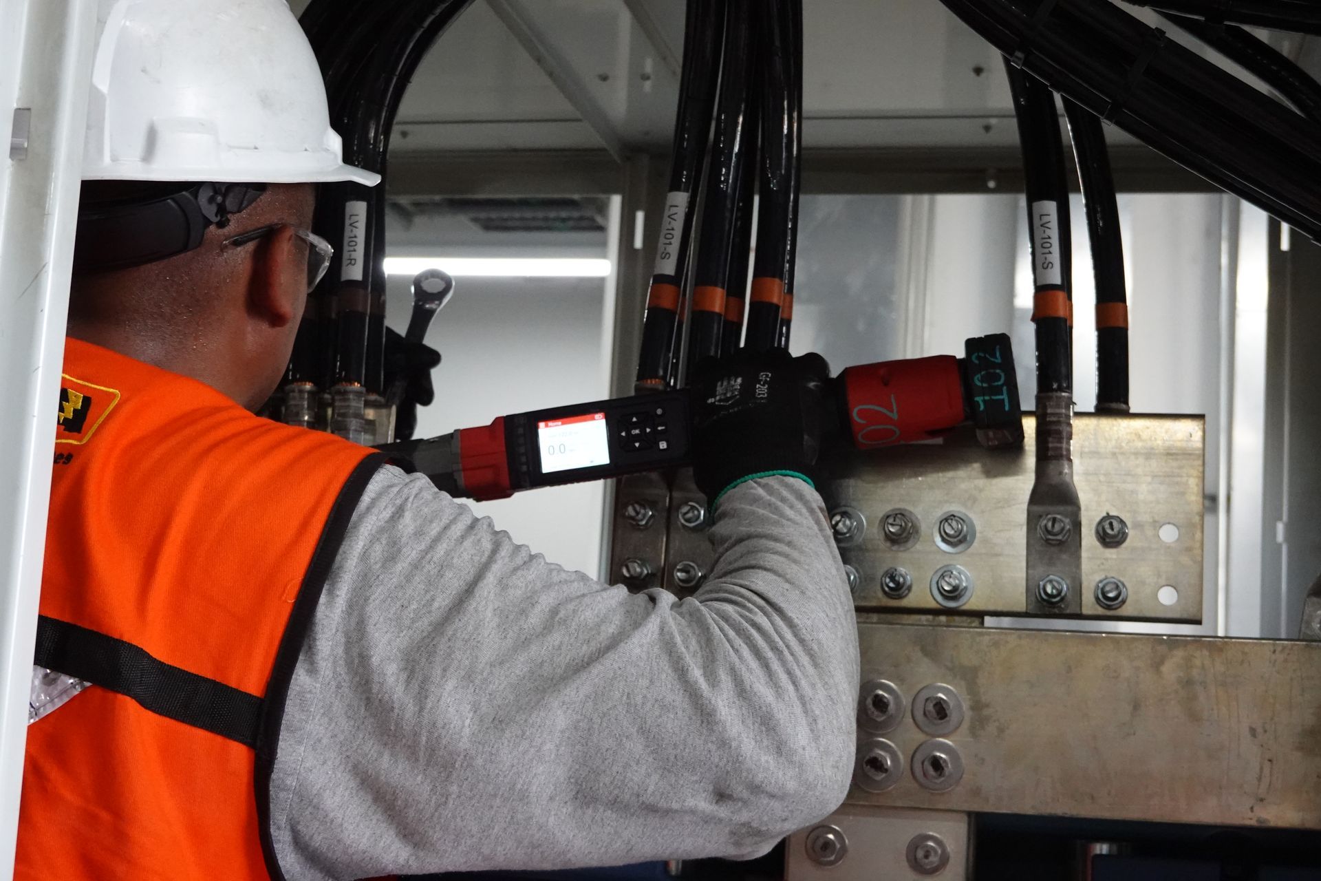 Un hombre que lleva un casco y un chaleco naranja está trabajando en una máquina.