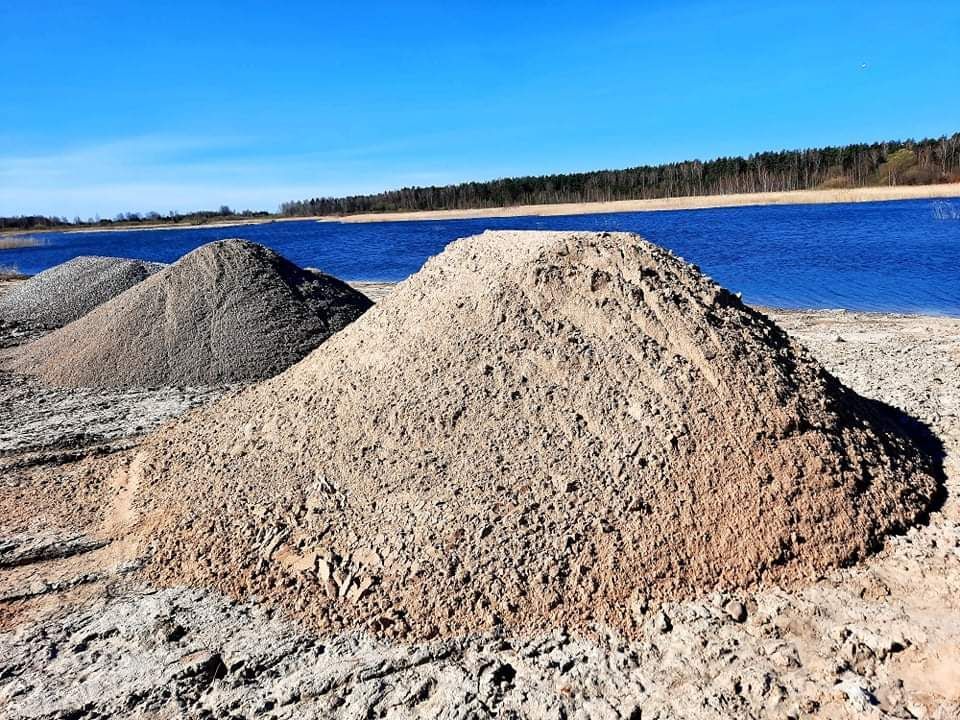 Prie vandens telkinio didelė smėlio krūva