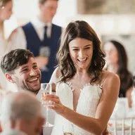 A bride and groom are toasting with champagne at their wedding reception.