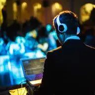 A man in a suit and headphones is using a laptop computer.