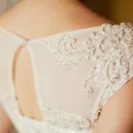 A close up of a woman 's back in a white wedding dress.