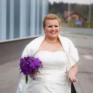 The bride is wearing a white dress and holding a bouquet of purple flowers.
