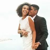 A man is kissing a woman on the cheek on their wedding day.