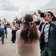 A bride and groom are holding sparklers at their wedding reception.