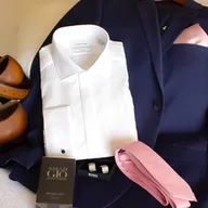 A man is wearing a tuxedo with a white shirt and a pink tie.