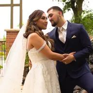 A bride and groom are holding hands and looking at each other.