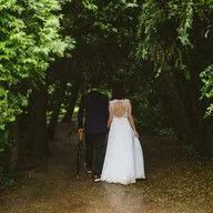 A bride and groom are walking through a forest.
