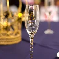 A champagne flute is sitting on a table next to a crown.
