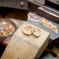 A pair of wedding rings sitting on top of a wooden block.