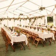 A large tent with tables and chairs set up for a wedding reception.