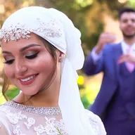 The bride is wearing a turban and smiling while the groom is standing behind her.