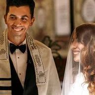 A bride and groom are standing next to each other in a church and smiling.