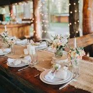 A table set for a wedding reception with plates , candles , and flowers.